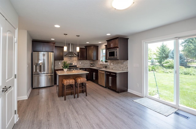 296 S 82nd St, West Des Moines, IA 50266 - kitchen featuring appliances with stainless steel finishes, wall chimney range hood, dark brown cabinetry, a breakfast bar area, and decorative backsplash