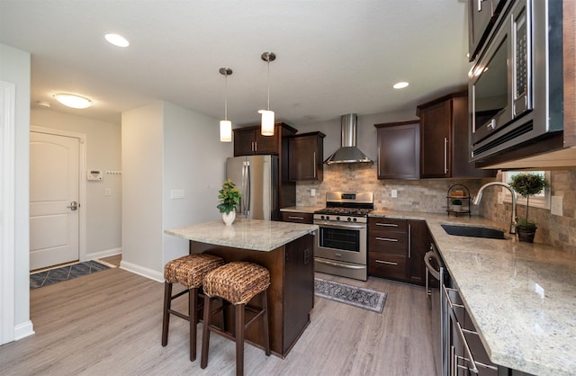 296 S 82nd St, West Des Moines, IA 50266 - kitchen featuring stainless steel appliances, wall chimney range hood, dark brown cabinets, a breakfast bar area, and light wood-type flooring