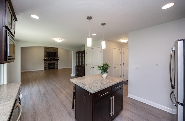296 S 82nd St, West Des Moines, IA 50266 - kitchen featuring freestanding refrigerator, dark wood-type flooring, a fireplace, open floor plan, and dark brown cabinetry