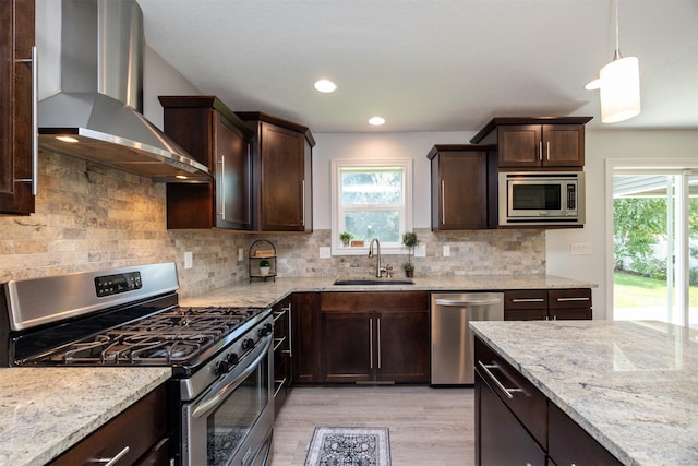 296 S 82nd St, West Des Moines, IA 50266 - kitchen featuring appliances with stainless steel finishes, wall chimney range hood, dark brown cabinetry, light wood finished floors, and light stone counters
