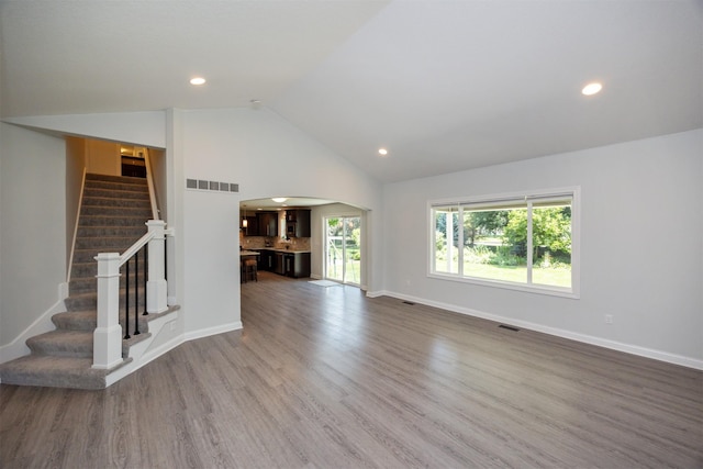 296 S 82nd St, West Des Moines, IA 50266 - unfurnished living room featuring arched walkways, stairway, wood finished floors, recessed lighting, and high vaulted ceiling