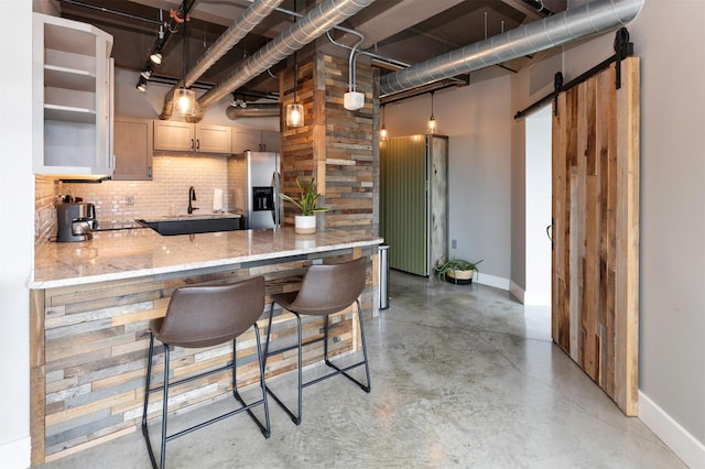 120 SW 5th St Unit 306, Des Moines, IA 50309 - kitchen featuring stainless steel refrigerator with ice dispenser, decorative backsplash, concrete flooring, a peninsula, and a barn door