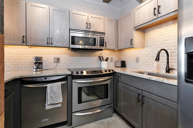 120 SW 5th St Unit 306, Des Moines, IA 50309 - kitchen with stainless steel appliances, tasteful backsplash, light stone countertops, and gray cabinetry