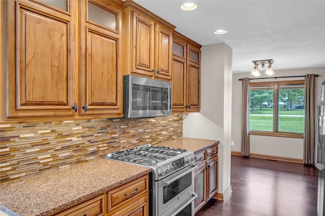 904 Pleasant St SE, Bondurant, IA 50035 - kitchen with appliances with stainless steel finishes, brown cabinetry, dark wood-style flooring, glass insert cabinets, and decorative backsplash