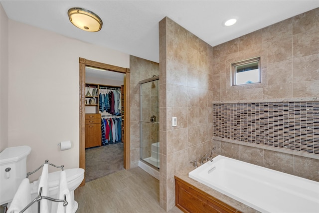 904 Pleasant St SE, Bondurant, IA 50035 - full bathroom featuring a bath, a stall shower, a walk in closet, and tile walls