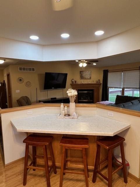 4806 Waller St, Ames, IA 50014 - kitchen with a ceiling fan, open floor plan, a fireplace, light wood-style flooring, and a breakfast bar