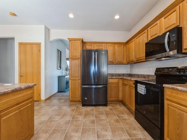 705 SE Whitetail Ln, Waukee, IA 50263 - kitchen with freestanding refrigerator, black / electric stove, arched walkways, brown cabinetry, and recessed lighting