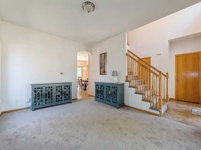 705 SE Whitetail Ln, Waukee, IA 50263 - unfurnished living room with arched walkways, carpet floors, and stairs