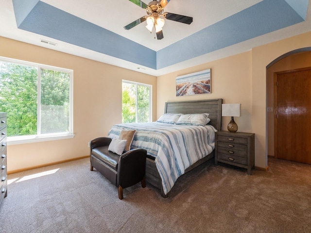 705 SE Whitetail Ln, Waukee, IA 50263 - carpeted bedroom featuring arched walkways, a raised ceiling, and ceiling fan