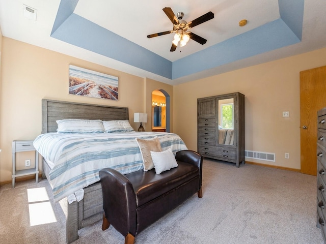 705 SE Whitetail Ln, Waukee, IA 50263 - bedroom with light carpet, arched walkways, a raised ceiling, and a ceiling fan