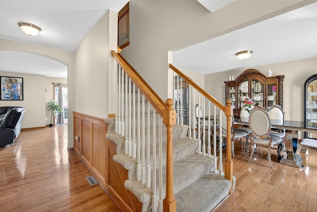 3413 Brook Run Dr, Des Moines, IA 50317 - stairway featuring arched walkways, wood finished floors, and a textured ceiling