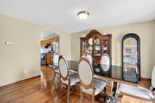3413 Brook Run Dr, Des Moines, IA 50317 - dining room featuring arched walkways, light wood-style flooring, and a textured ceiling