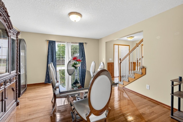 3413 Brook Run Dr, Des Moines, IA 50317 - dining area with light wood finished floors, stairs, a textured ceiling, and decorative columns
