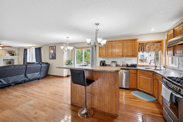 3413 Brook Run Dr, Des Moines, IA 50317 - kitchen with stainless steel appliances, a chandelier, light wood finished floors, open floor plan, and a textured ceiling