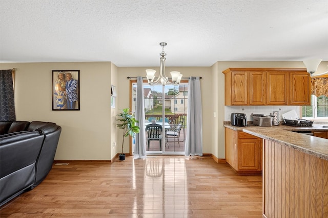 3413 Brook Run Dr, Des Moines, IA 50317 - kitchen featuring light wood-type flooring, a chandelier, open floor plan, decorative light fixtures, and a textured ceiling