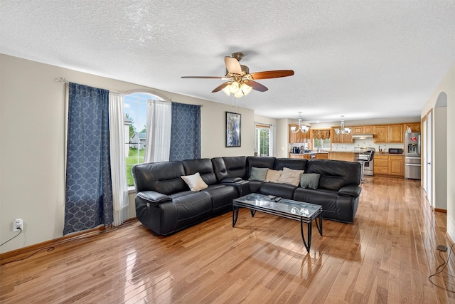 3413 Brook Run Dr, Des Moines, IA 50317 - living room featuring light wood-style floors, a textured ceiling, a ceiling fan, and a chandelier