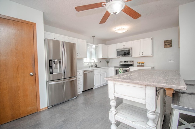 5420 SW 13th St, Des Moines, IA 50315 - kitchen with stainless steel appliances, white cabinets, light countertops, a ceiling fan, and wood finished floors