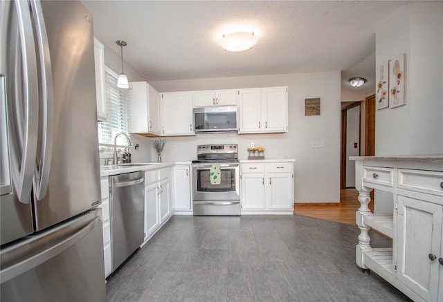 5420 SW 13th St, Des Moines, IA 50315 - kitchen featuring stainless steel appliances, white cabinets, wood finished floors, light countertops, and hanging light fixtures