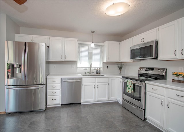 5420 SW 13th St, Des Moines, IA 50315 - kitchen featuring stainless steel appliances, white cabinetry, light countertops, a textured ceiling, and hanging light fixtures