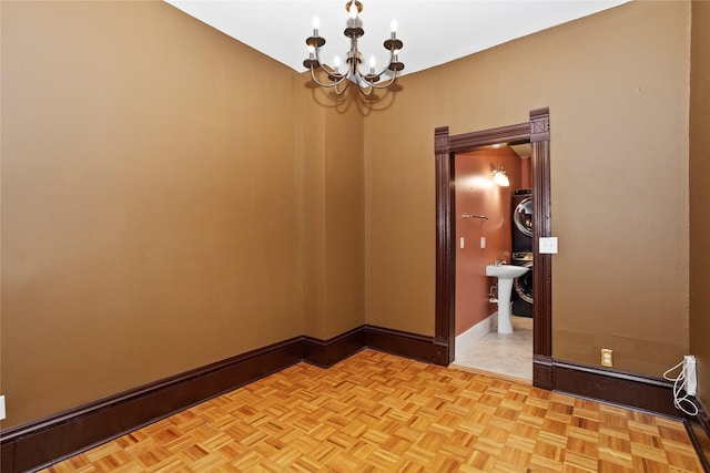 658 20th St, Des Moines, IA 50314 - empty room featuring stacked washing machine and dryer and a chandelier