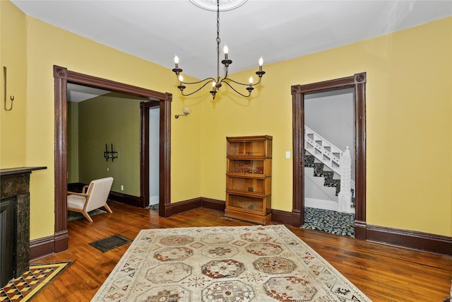 658 20th St, Des Moines, IA 50314 - foyer entrance with a chandelier, dark wood-style floors, a tiled fireplace, and stairway