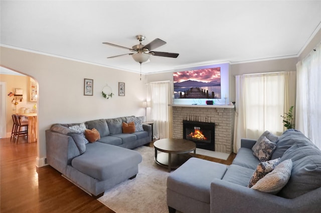 618 Arthur Ave, Des Moines, IA 50313 - living room with wood finished floors, a ceiling fan, a fireplace, ornamental molding, and arched walkways