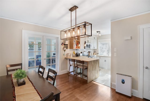 618 Arthur Ave, Des Moines, IA 50313 - dining area featuring light wood-type flooring, french doors, and ornamental molding