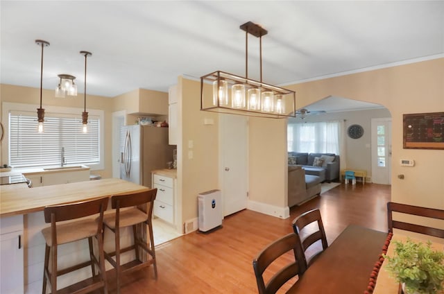 618 Arthur Ave, Des Moines, IA 50313 - dining area with arched walkways, light wood-style flooring, and crown molding