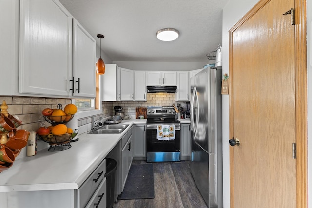 1324 College Ave, Des Moines, IA 50314 - kitchen featuring appliances with stainless steel finishes, under cabinet range hood, dark wood finished floors, tasteful backsplash, and light countertops