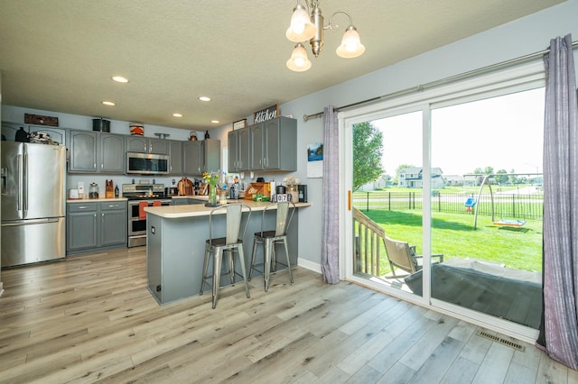 550 25th St SE, Altoona, IA 50009 - kitchen featuring appliances with stainless steel finishes, gray cabinetry, light wood-style floors, a chandelier, and recessed lighting