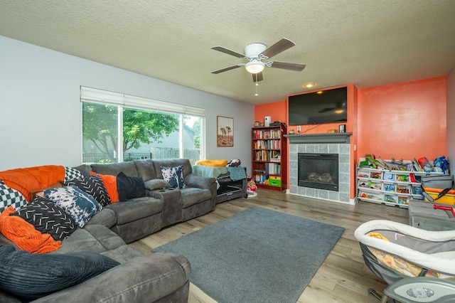 550 25th St SE, Altoona, IA 50009 - living room with a ceiling fan, wood finished floors, a fireplace, and a textured ceiling
