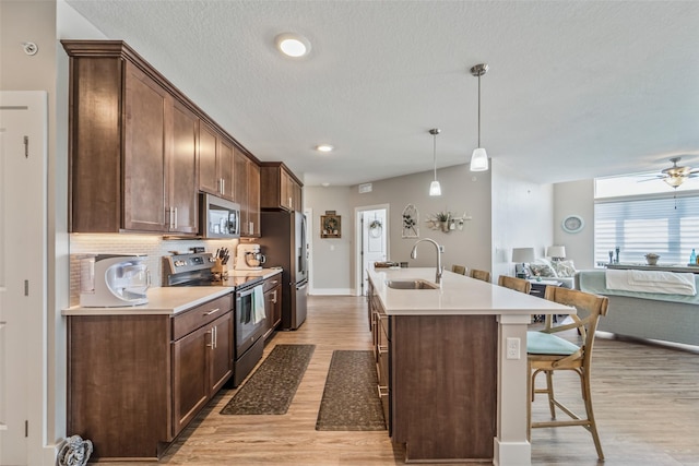 9065 Bishop Dr Unit 314, West Des Moines, IA 50266 - kitchen featuring appliances with stainless steel finishes, light wood-style flooring, a kitchen island with sink, a breakfast bar area, and recessed lighting