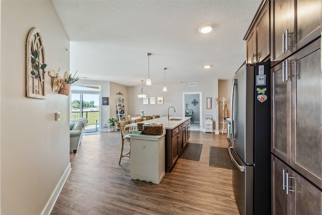 9065 Bishop Dr Unit 314, West Des Moines, IA 50266 - kitchen featuring freestanding refrigerator, a center island with sink, dark wood finished floors, a breakfast bar area, and open floor plan