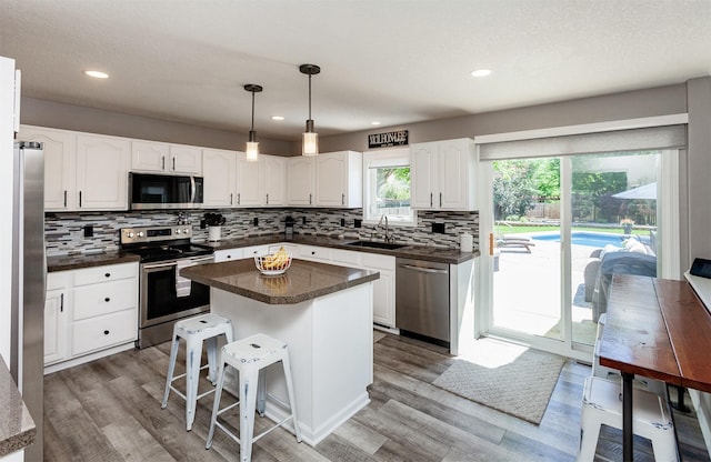 2507 135th St, Urbandale, IA 50323 - kitchen featuring appliances with stainless steel finishes, dark countertops, tasteful backsplash, white cabinetry, and recessed lighting