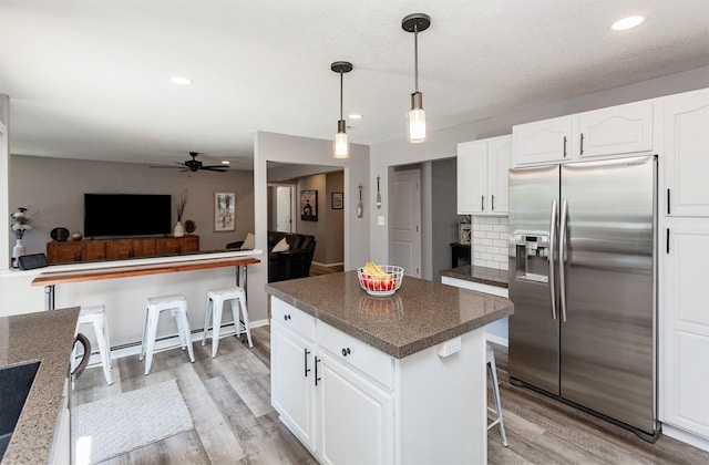 2507 135th St, Urbandale, IA 50323 - kitchen featuring stainless steel fridge with ice dispenser, ceiling fan, light wood-type flooring, a kitchen island, and white cabinets