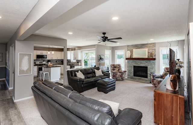 2507 135th St, Urbandale, IA 50323 - living room featuring recessed lighting, ceiling fan, light carpet, a stone fireplace, and a textured ceiling