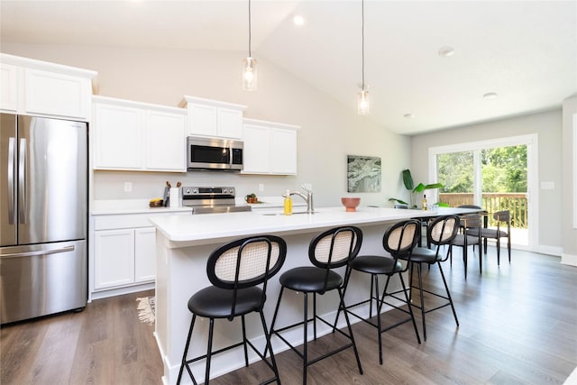 2529 SE Integra Ave, West Des Moines, IA 50265 - kitchen with stainless steel appliances, an island with sink, light countertops, a breakfast bar area, and high vaulted ceiling