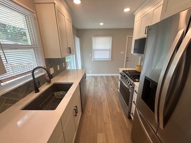 3412 Crestmoor Pl, Des Moines, IA 50310 - kitchen with stainless steel appliances, decorative backsplash, light countertops, light wood finished floors, and recessed lighting