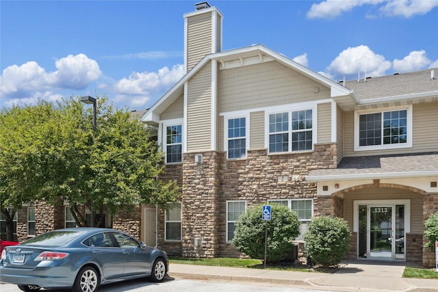 1313 SE University Ave Unit 206, Waukee, IA 50263 - view of property featuring stone siding, a chimney, and roof with shingles