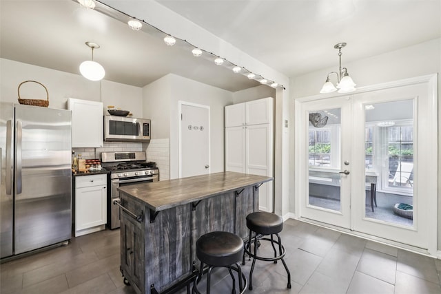 3923 Maquoketa Dr, Des Moines, IA 50311 - kitchen featuring appliances with stainless steel finishes, a chandelier, a kitchen breakfast bar, and white cabinets