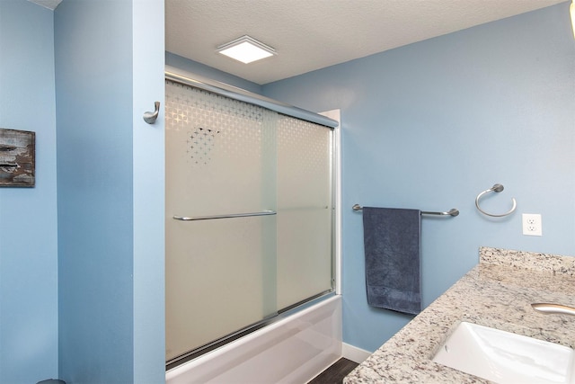 13001 Twana Dr, Urbandale, IA 50323 - bathroom featuring double vanity, a textured ceiling, bath / shower combo with glass door, and wood finished floors