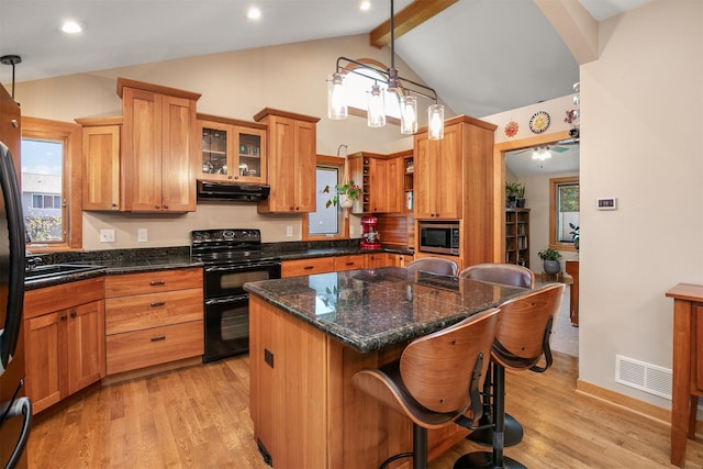 13001 Twana Dr, Urbandale, IA 50323 - kitchen with range with two ovens, under cabinet range hood, stainless steel microwave, beam ceiling, and a kitchen breakfast bar