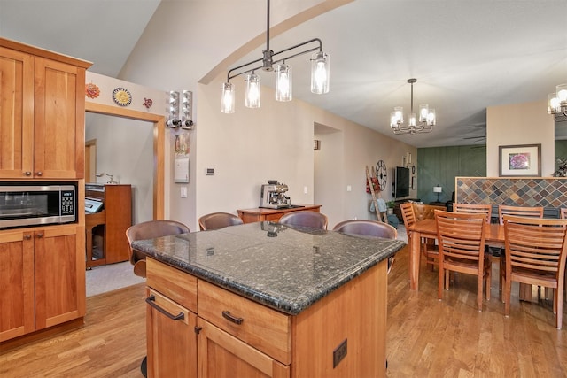 13001 Twana Dr, Urbandale, IA 50323 - kitchen with stainless steel microwave, a chandelier, light wood finished floors, backsplash, and decorative light fixtures