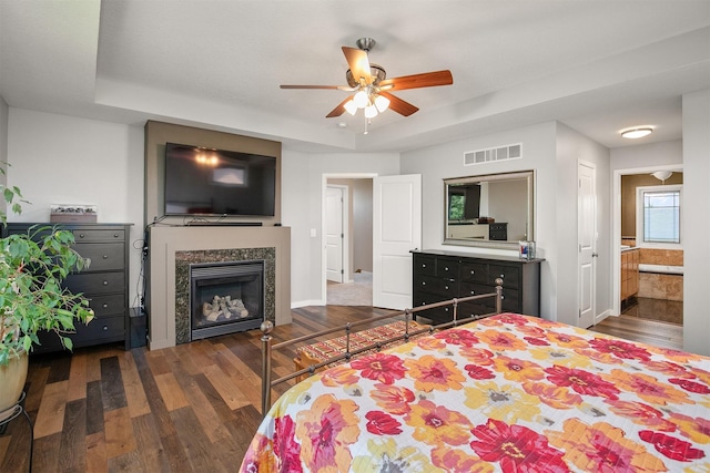 13001 Twana Dr, Urbandale, IA 50323 - bedroom featuring wood finished floors, a glass covered fireplace, a raised ceiling, and ensuite bathroom