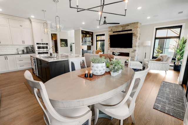 710 Peace St Unit 3D, Pella, IA 50219 - dining area with a chandelier, recessed lighting, light wood-type flooring, and a fireplace