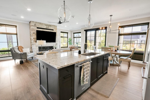 710 Peace St Unit 3D, Pella, IA 50219 - kitchen featuring stainless steel dishwasher, crown molding, dark cabinets, open floor plan, and a center island with sink
