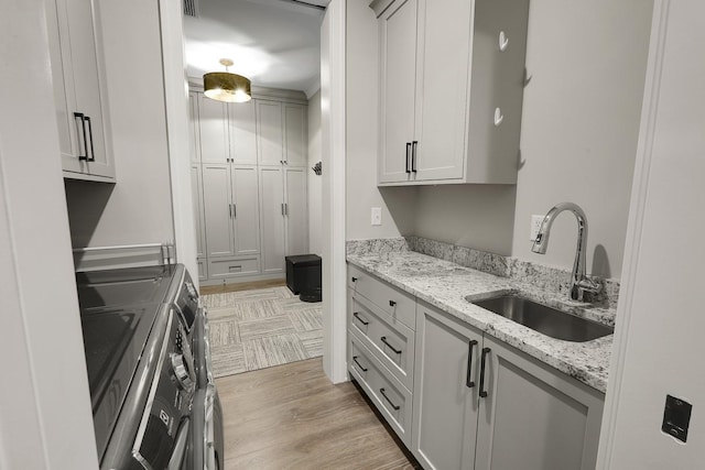 710 Peace St Unit 3D, Pella, IA 50219 - laundry room featuring washing machine and clothes dryer, cabinet space, and light wood-style flooring