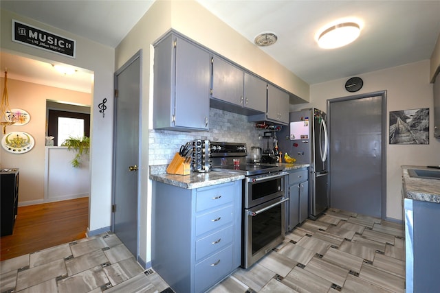 3600 Brinkwood Rd, Des Moines, IA 50310 - kitchen with appliances with stainless steel finishes, tasteful backsplash, under cabinet range hood, light countertops, and gray cabinets