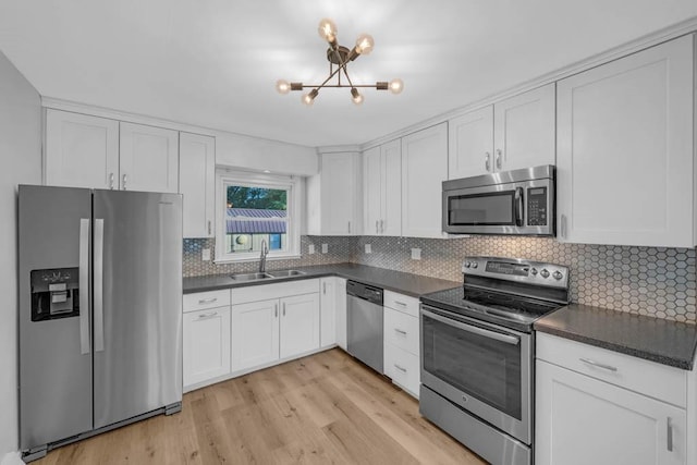 1515 Chance Ct, Adel, IA 50003 - kitchen featuring stainless steel appliances, dark countertops, a chandelier, white cabinetry, and light wood-style flooring