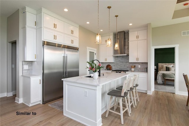 790 Hamilton Rd, Waukee, IA 50263 - kitchen with wall chimney range hood, built in refrigerator, decorative backsplash, white cabinetry, and recessed lighting